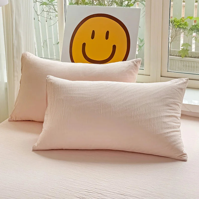 Set of two ultra-soft cotton-blend pillowcases in a minimalist solid colour, styled on a neutral-toned bed for a relaxed, cosy look.