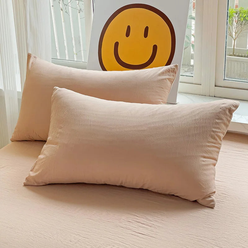 Set of two ultra-soft cotton-blend pillowcases in a minimalist solid colour, styled on a neutral-toned bed for a relaxed, cosy look.