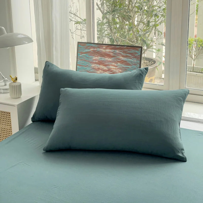 Set of two ultra-soft cotton-blend pillowcases in a minimalist solid colour, styled on a neutral-toned bed for a relaxed, cosy look.