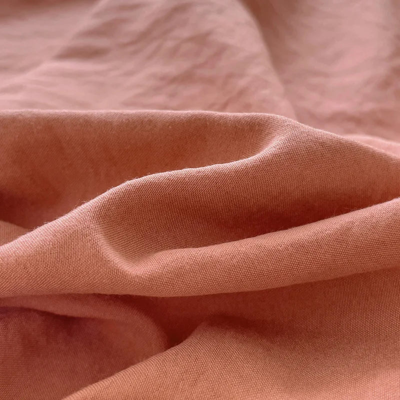 Set of two ultra-soft cotton-blend pillowcases in a minimalist solid colour, styled on a neutral-toned bed for a relaxed, cosy look.