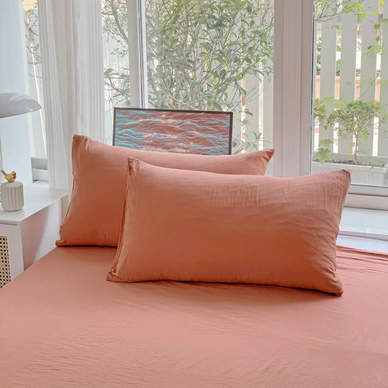 Set of two ultra-soft cotton-blend pillowcases in a minimalist solid colour, styled on a neutral-toned bed for a relaxed, cosy look.