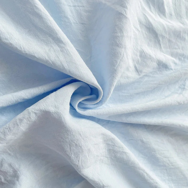 Set of two ultra-soft cotton-blend pillowcases in a minimalist solid colour, styled on a neutral-toned bed for a relaxed, cosy look.