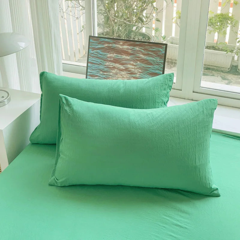 Set of two ultra-soft cotton-blend pillowcases in a minimalist solid colour, styled on a neutral-toned bed for a relaxed, cosy look.