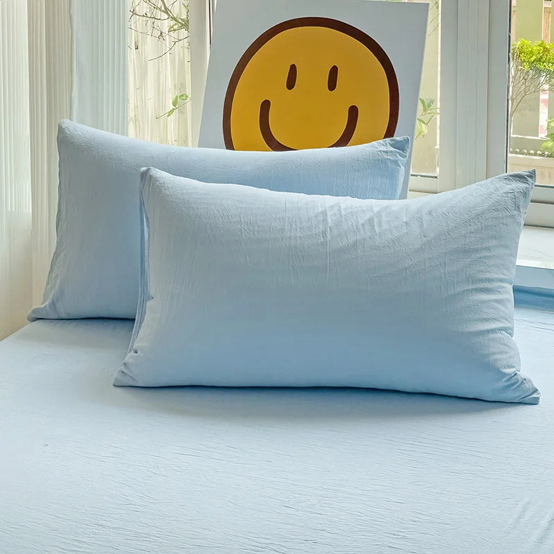 Set of two ultra-soft cotton-blend pillowcases in a minimalist solid colour, styled on a neutral-toned bed for a relaxed, cosy look.