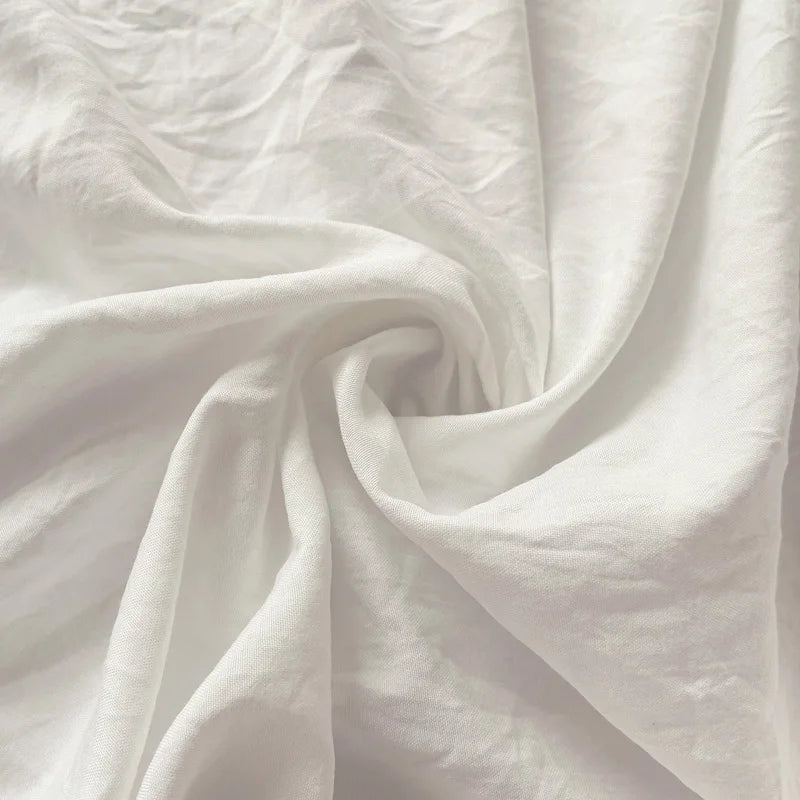 Set of two ultra-soft cotton-blend pillowcases in a minimalist solid colour, styled on a neutral-toned bed for a relaxed, cosy look.
