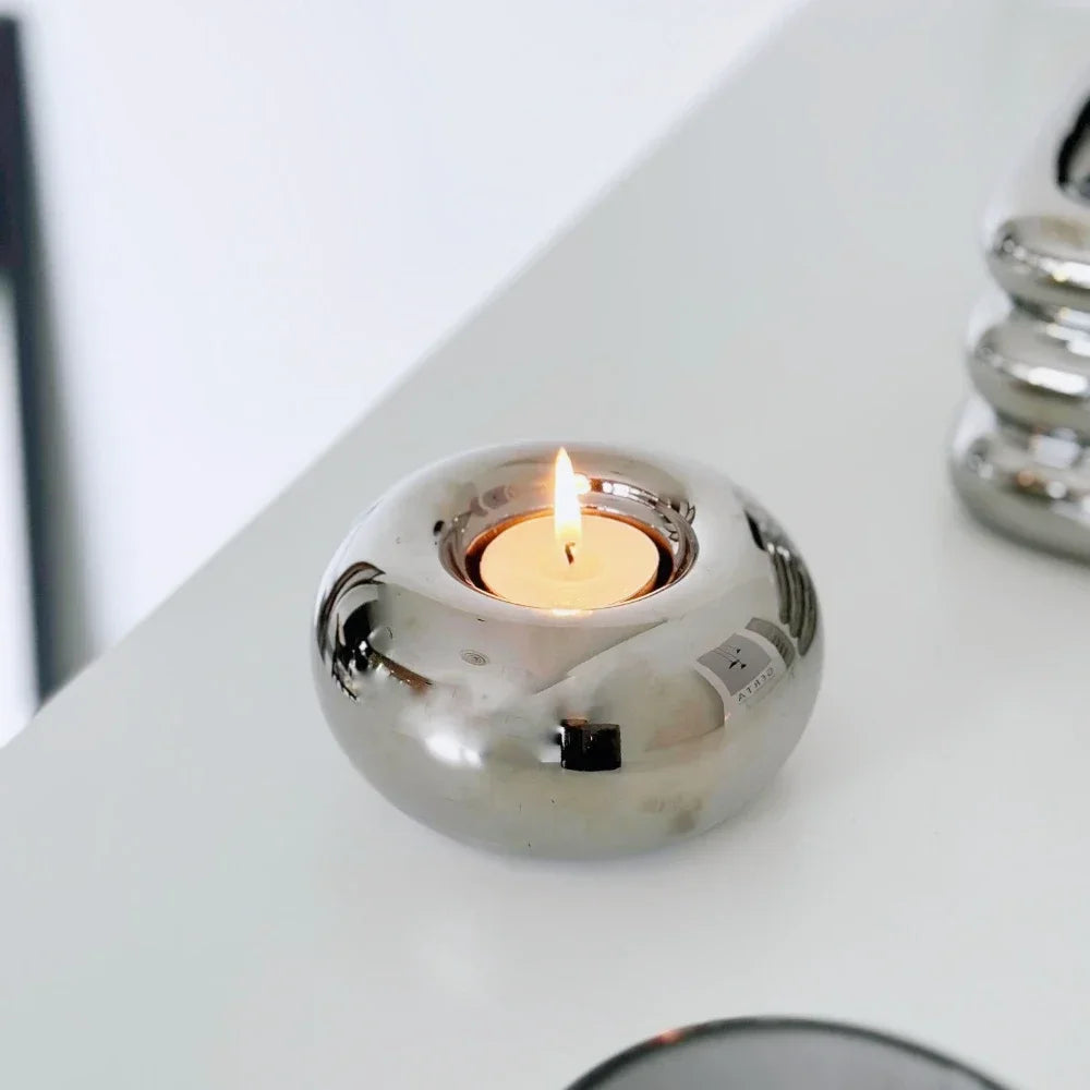 Modern silver ceramic candle holder with a sleek cylindrical design, shown in two sizes on a neutral-toned surface.