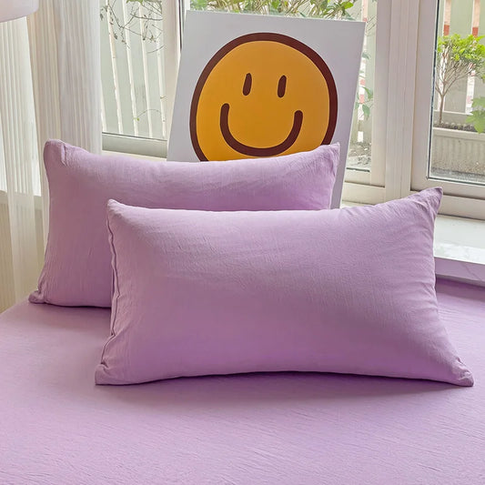Set of two ultra-soft cotton-blend pillowcases in a minimalist solid colour, styled on a neutral-toned bed for a relaxed, cosy look.